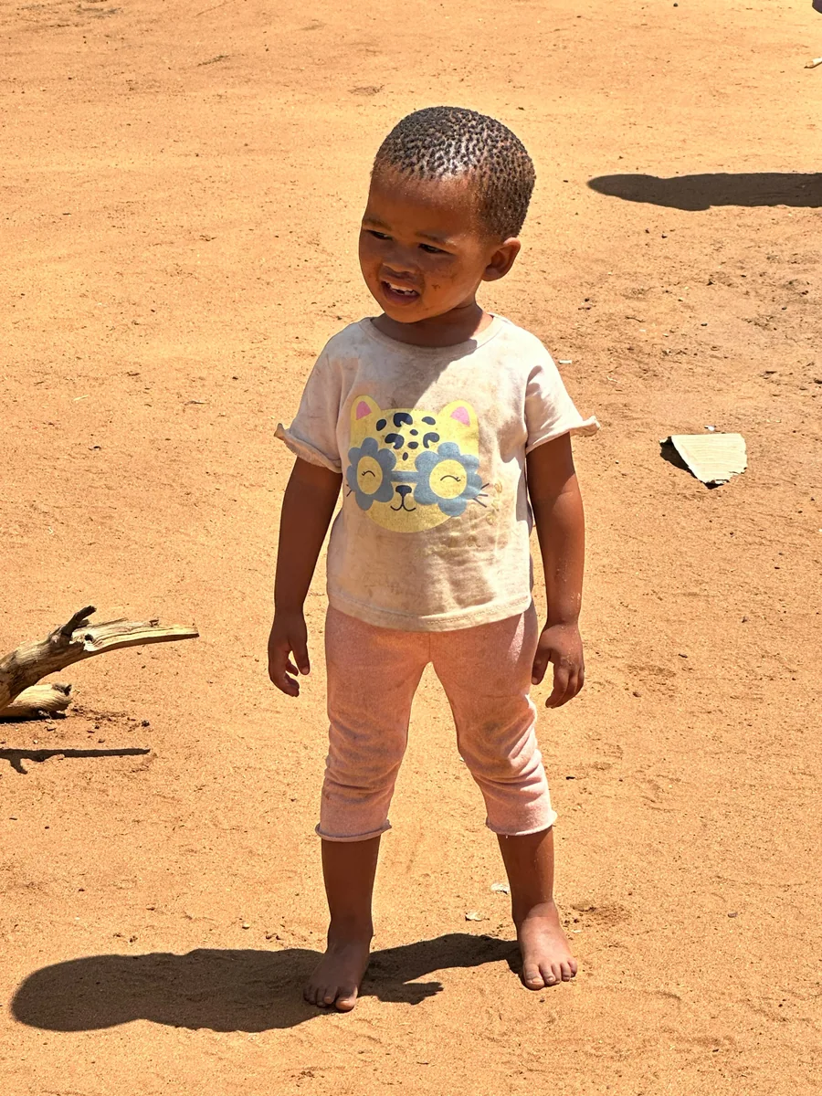 A young child standing outdoors in the sunshine