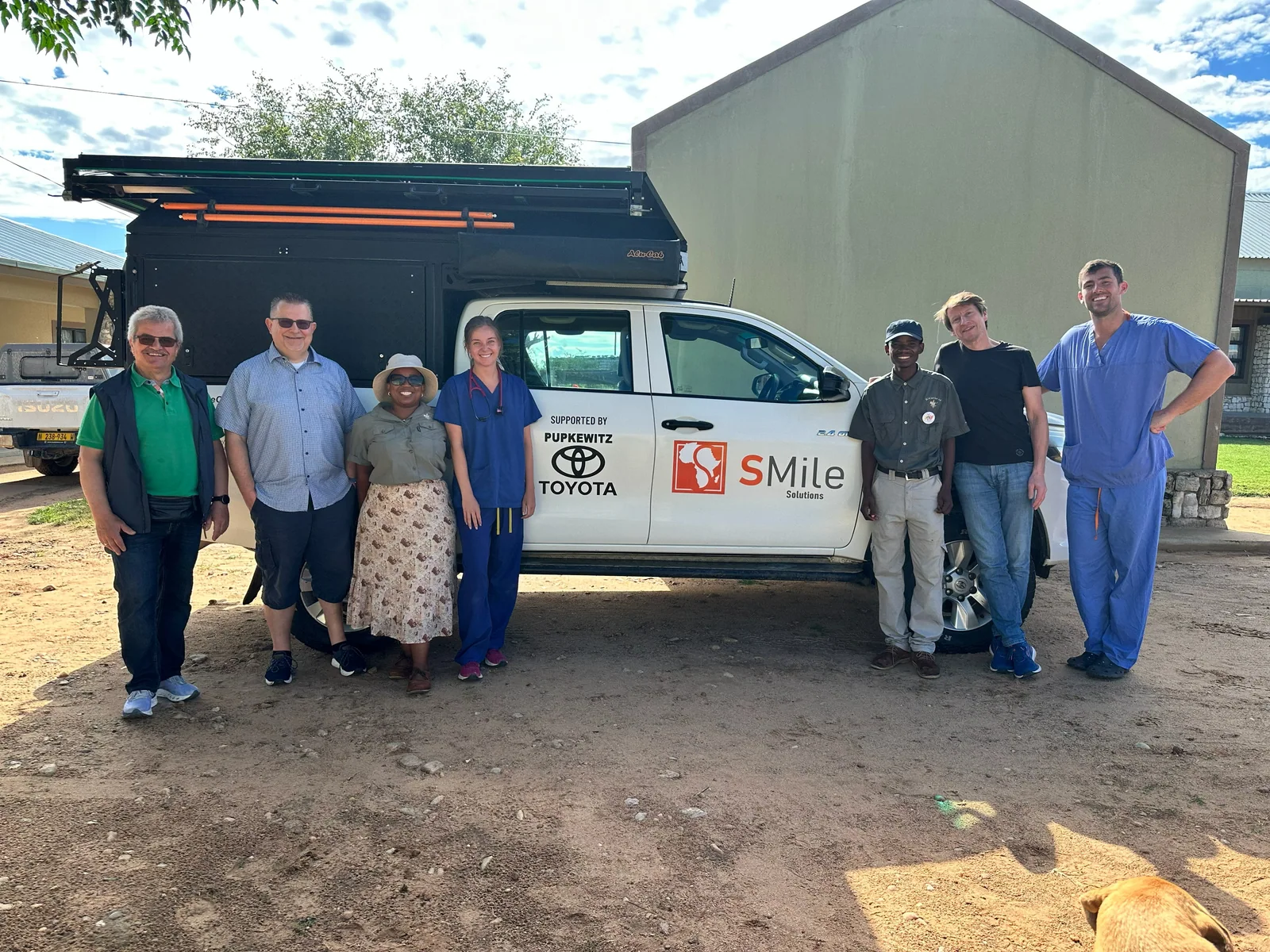 A group standing beside the mobile health pickup outside a clinic building